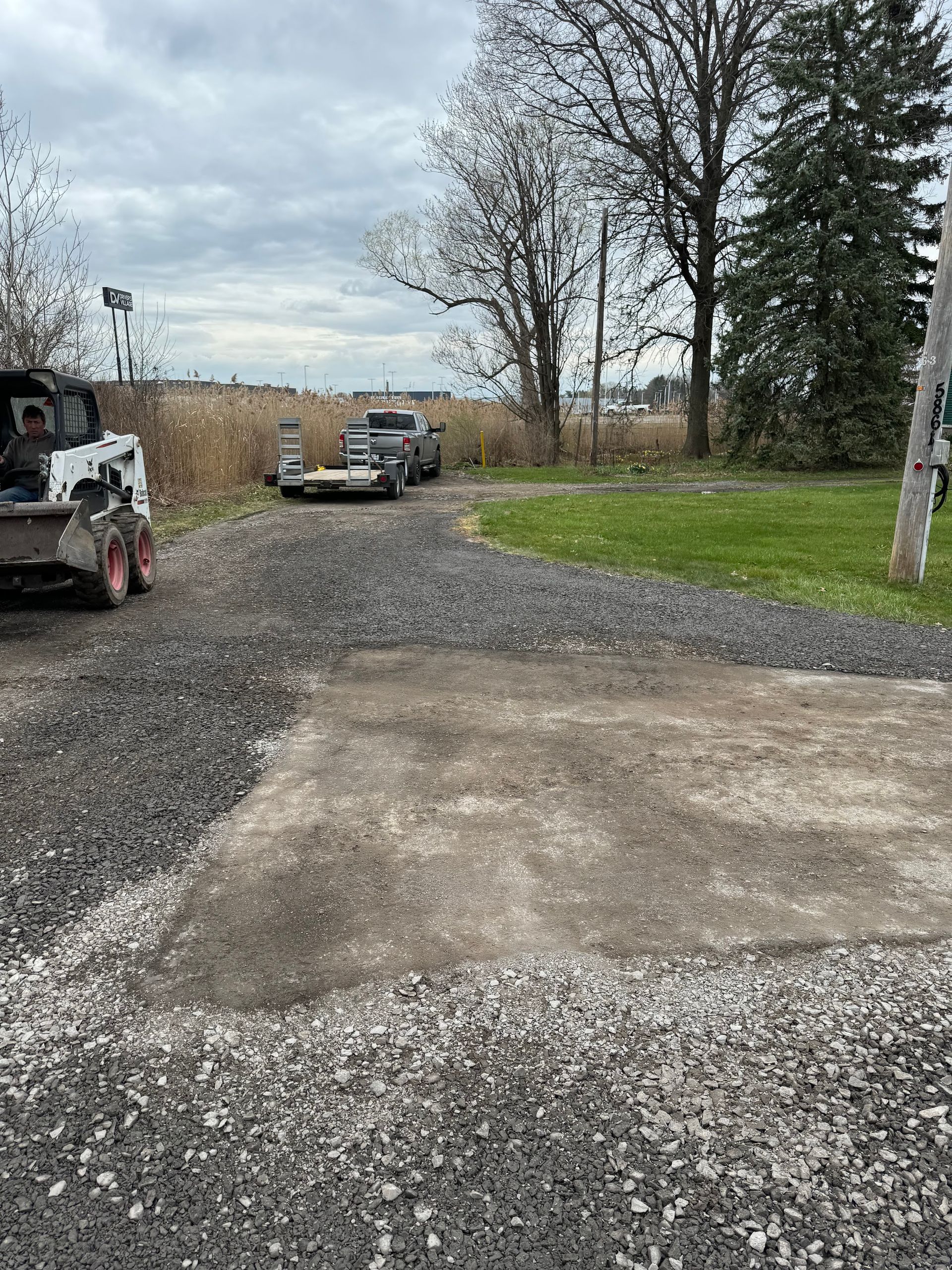 A bobcat is parked in the middle of a gravel road.