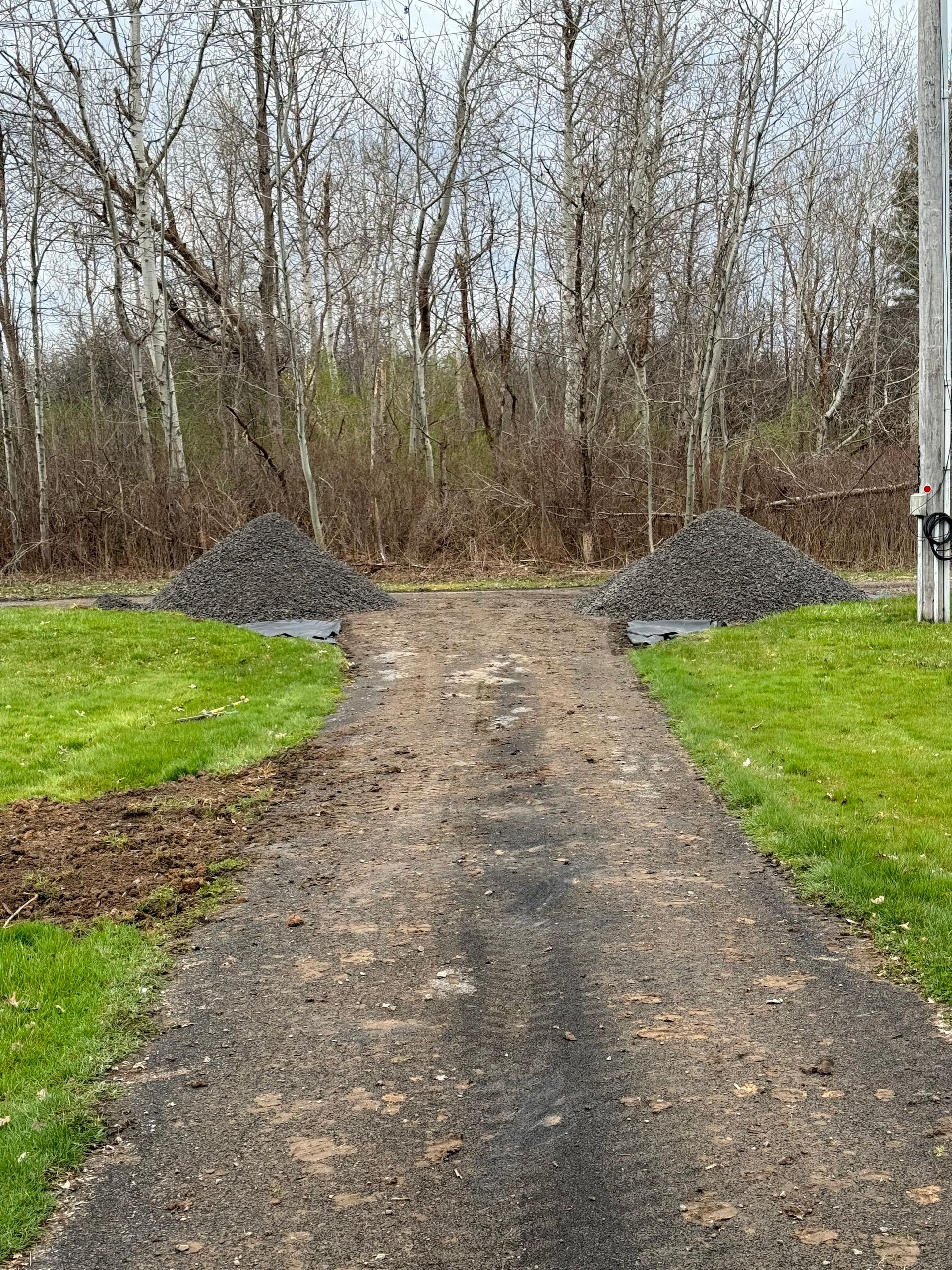 There are two piles of gravel on the side of the road.