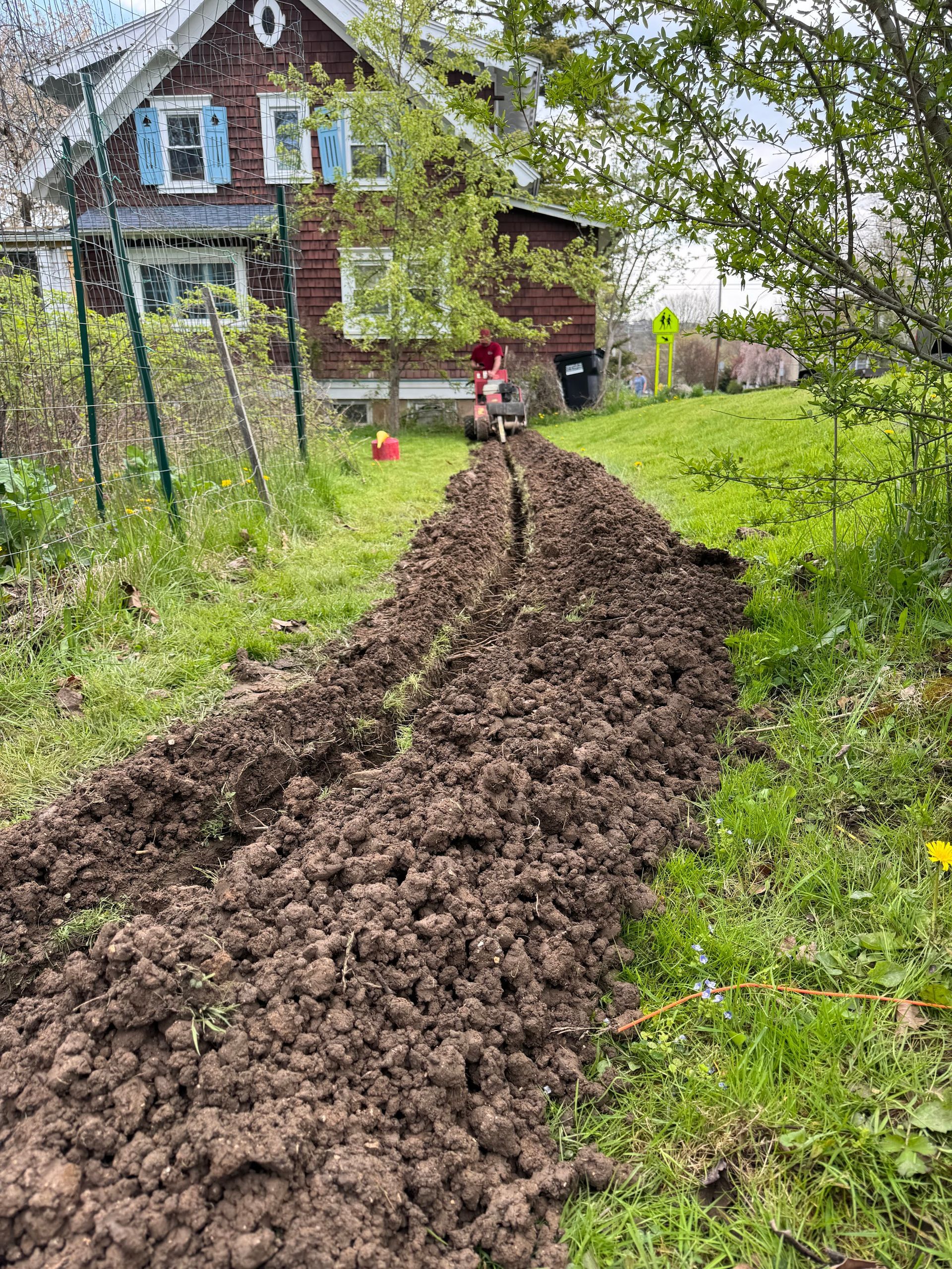 A pile of dirt is sitting in the grass in front of a house.