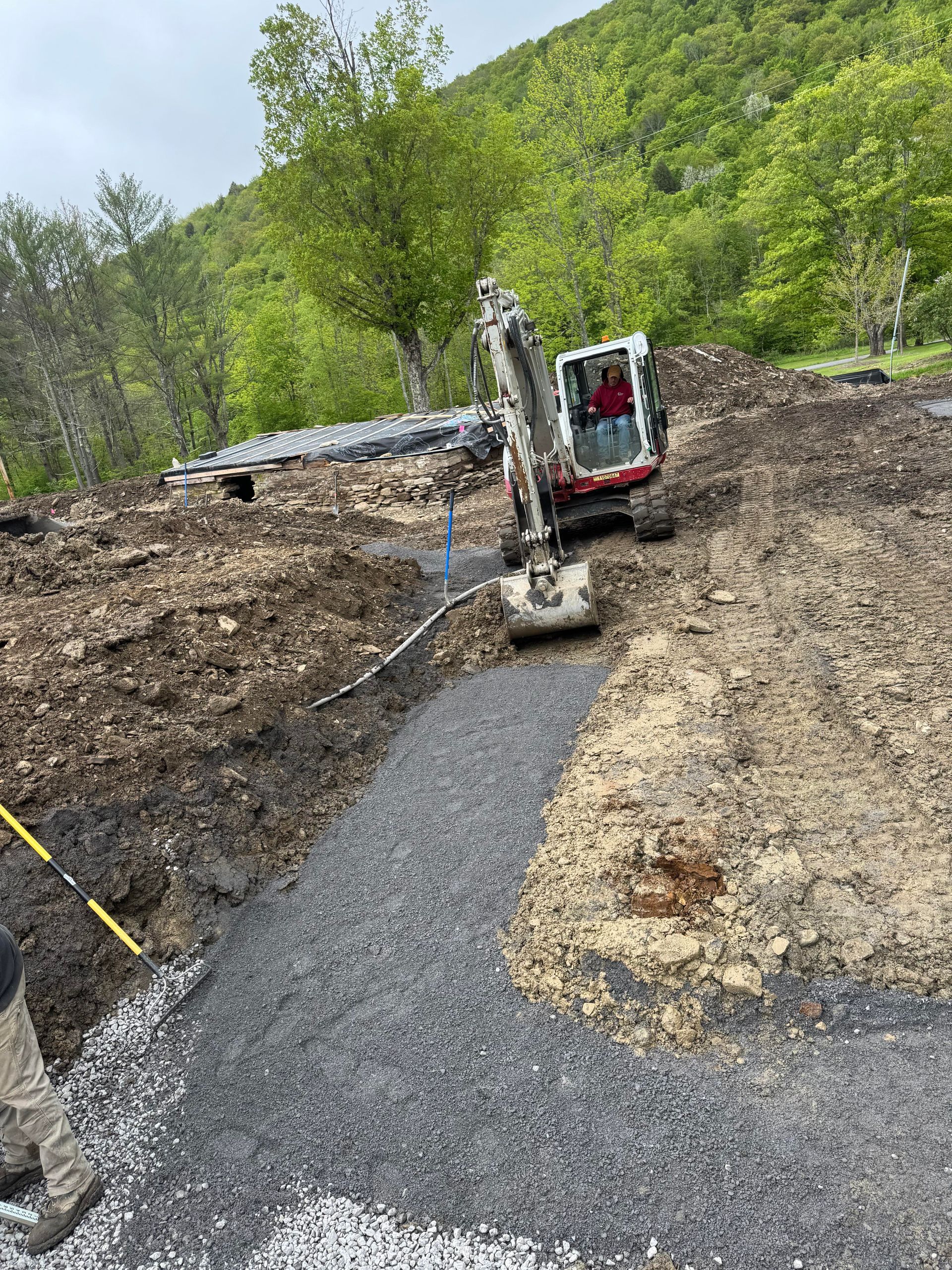 Mini excavator digging a gravel path on a hillside, preparing for construction.