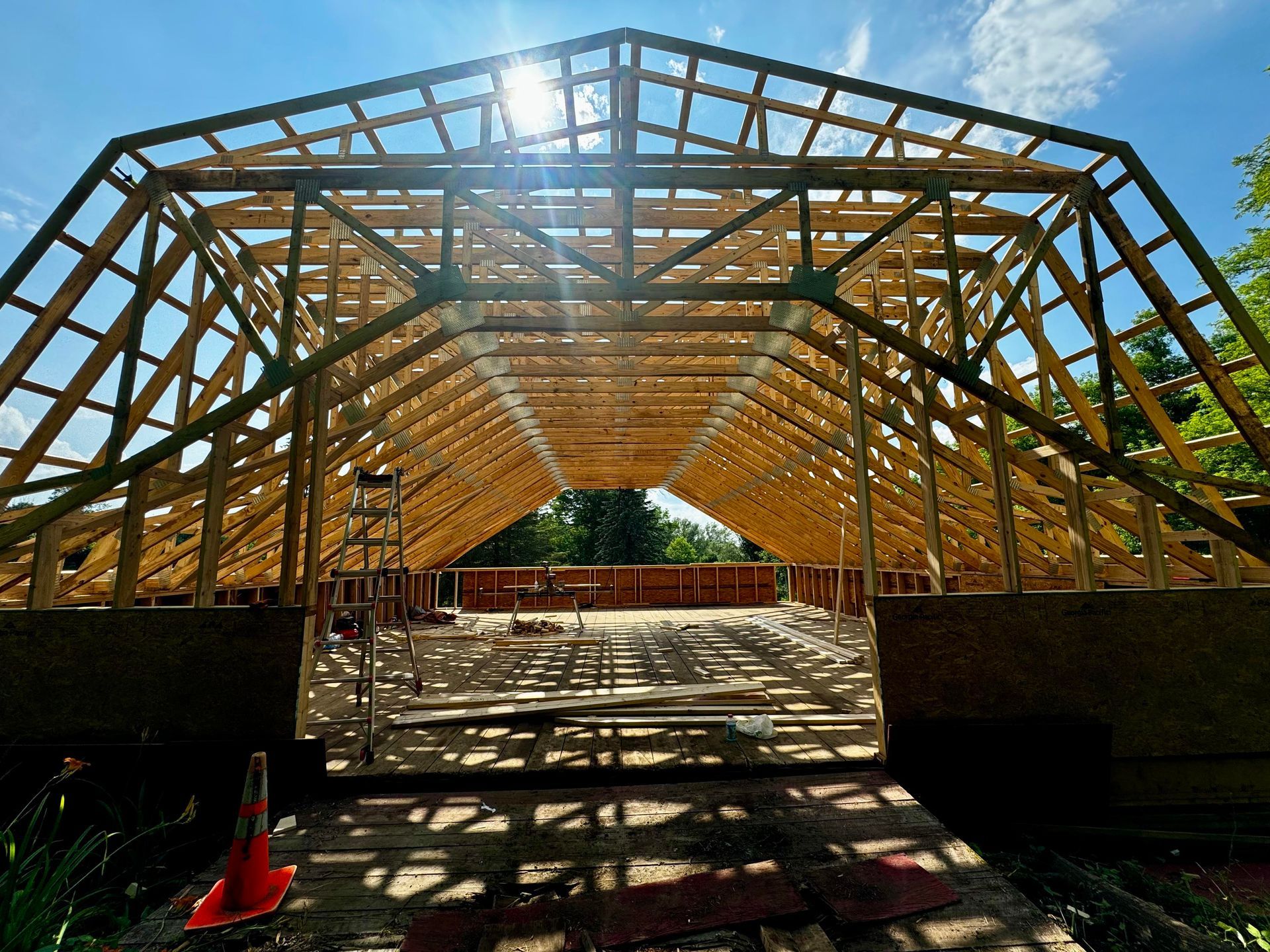 Wooden roof framing under construction; bright sunlight.
