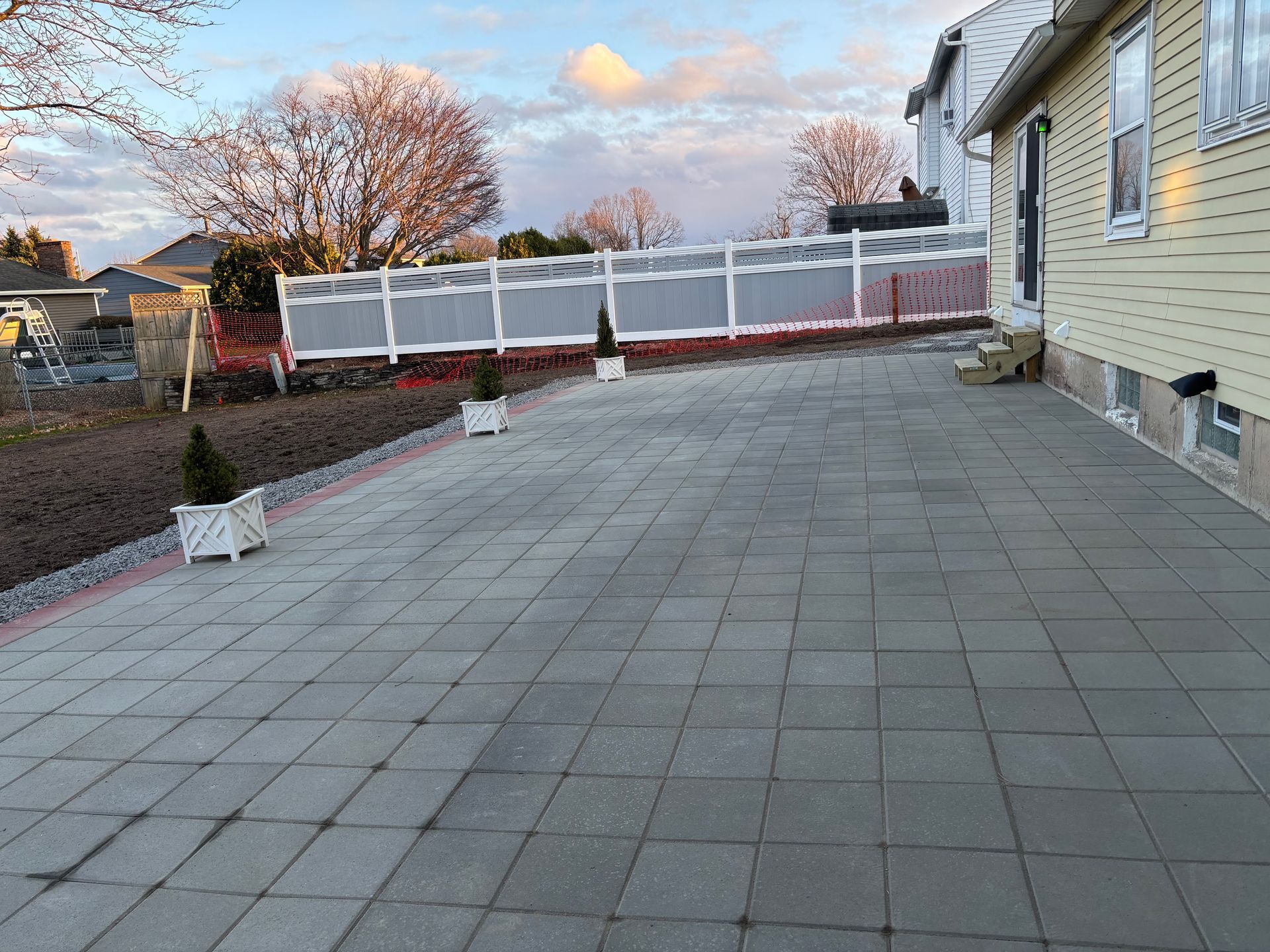 A large patio with a white fence and planters in front of a house.