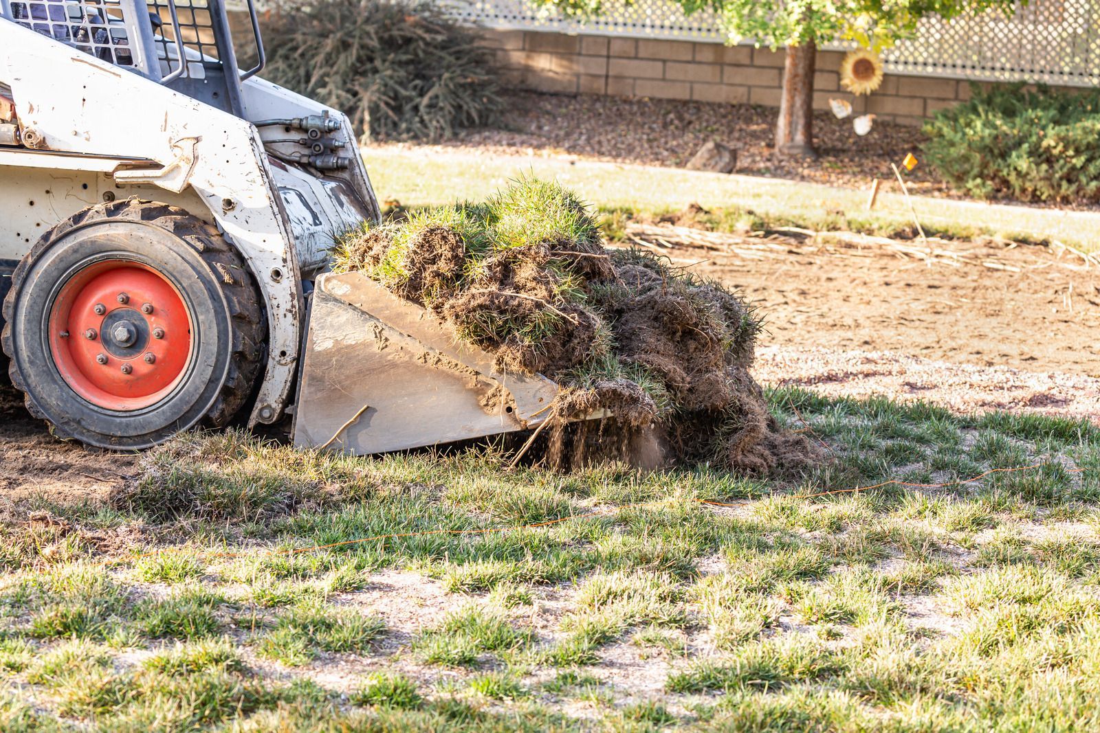 A bulldozer is moving dirt in a yard.