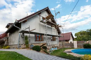 A house is being remodeled with scaffolding and a pool in the backyard.