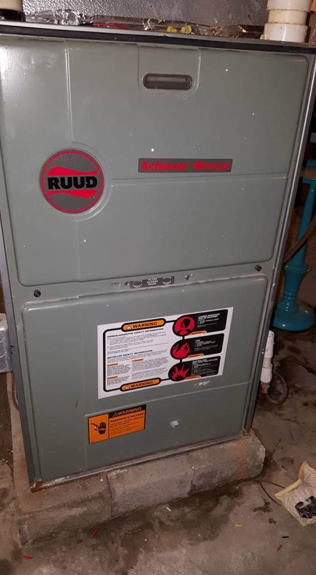 A furnace is sitting on top of a concrete floor in a basement.