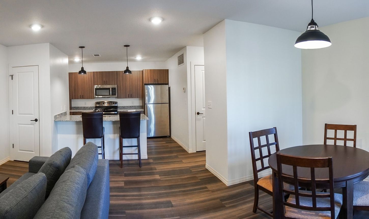 A living room with a couch , table , chairs and a kitchen.