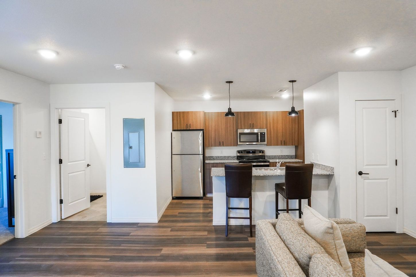 A living room with a couch and a kitchen with stainless steel appliances.