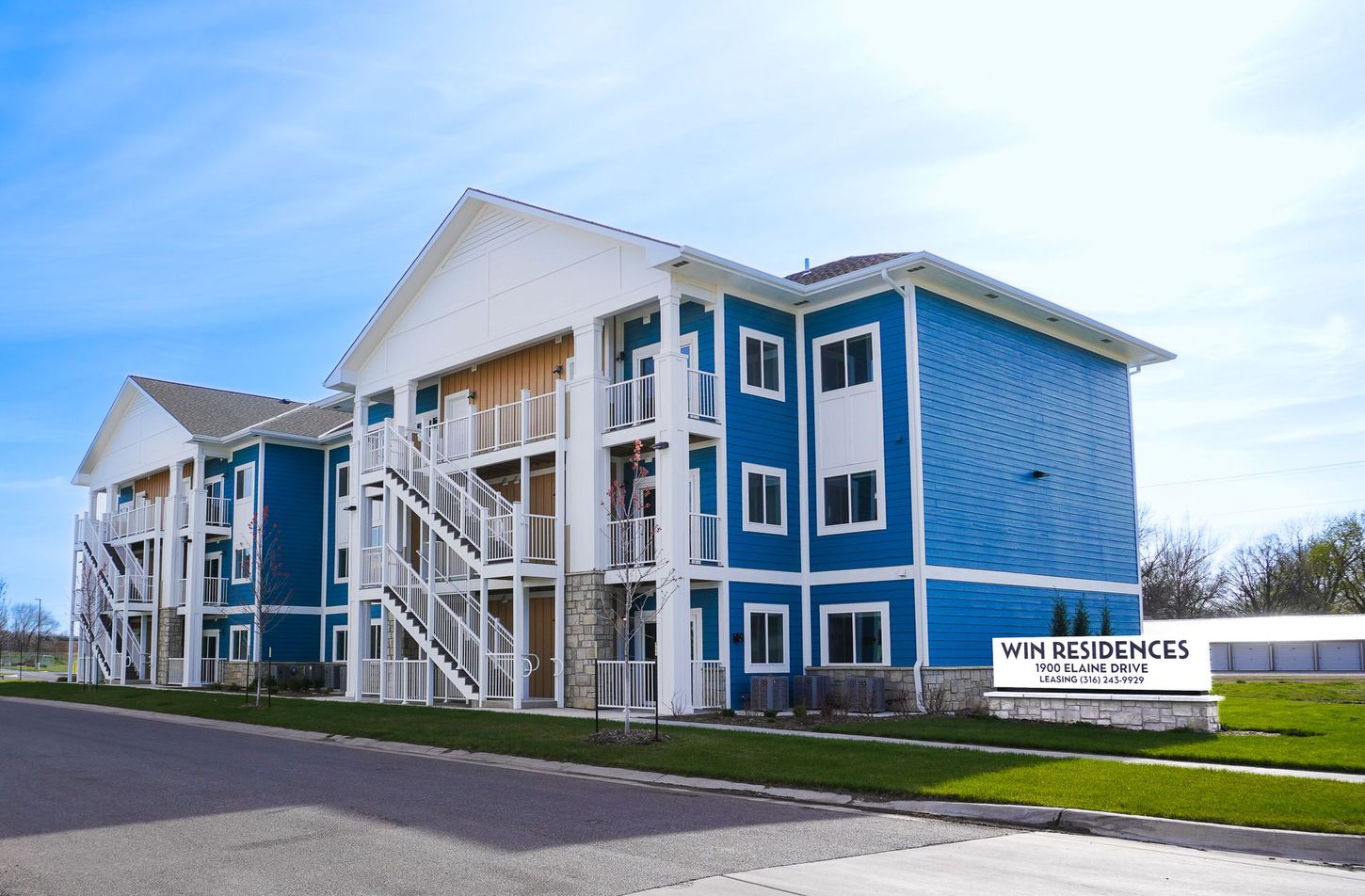 A blue and white apartment building with stairs leading up to it