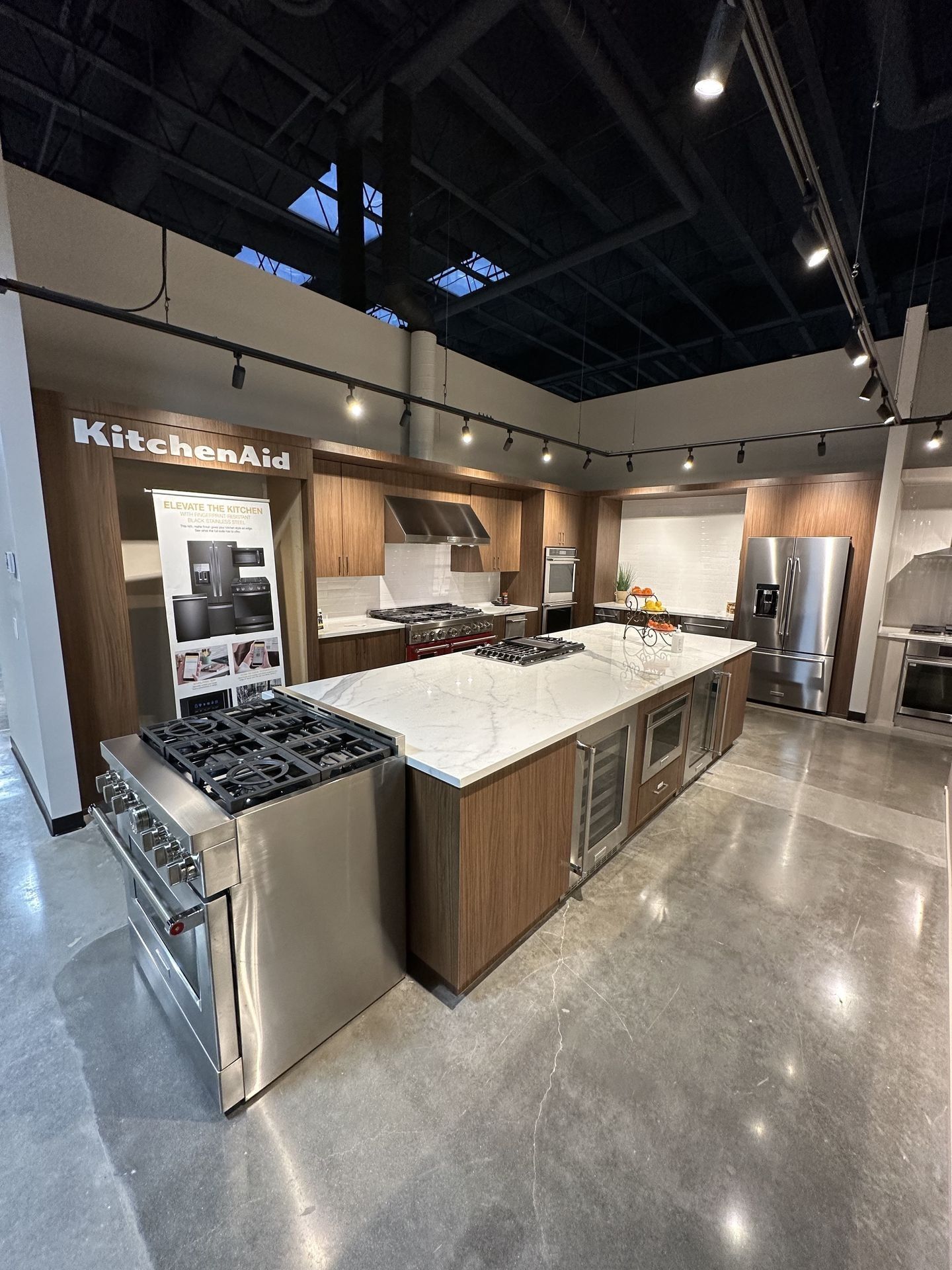 A kitchen with stainless steel appliances and wooden cabinets in a showroom.