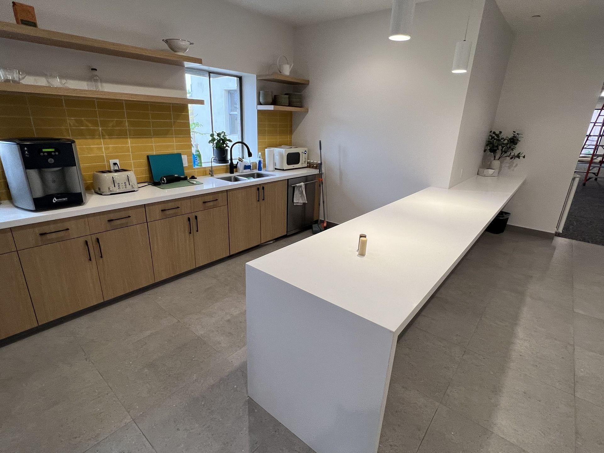 A kitchen with a long white counter top and wooden cabinets.