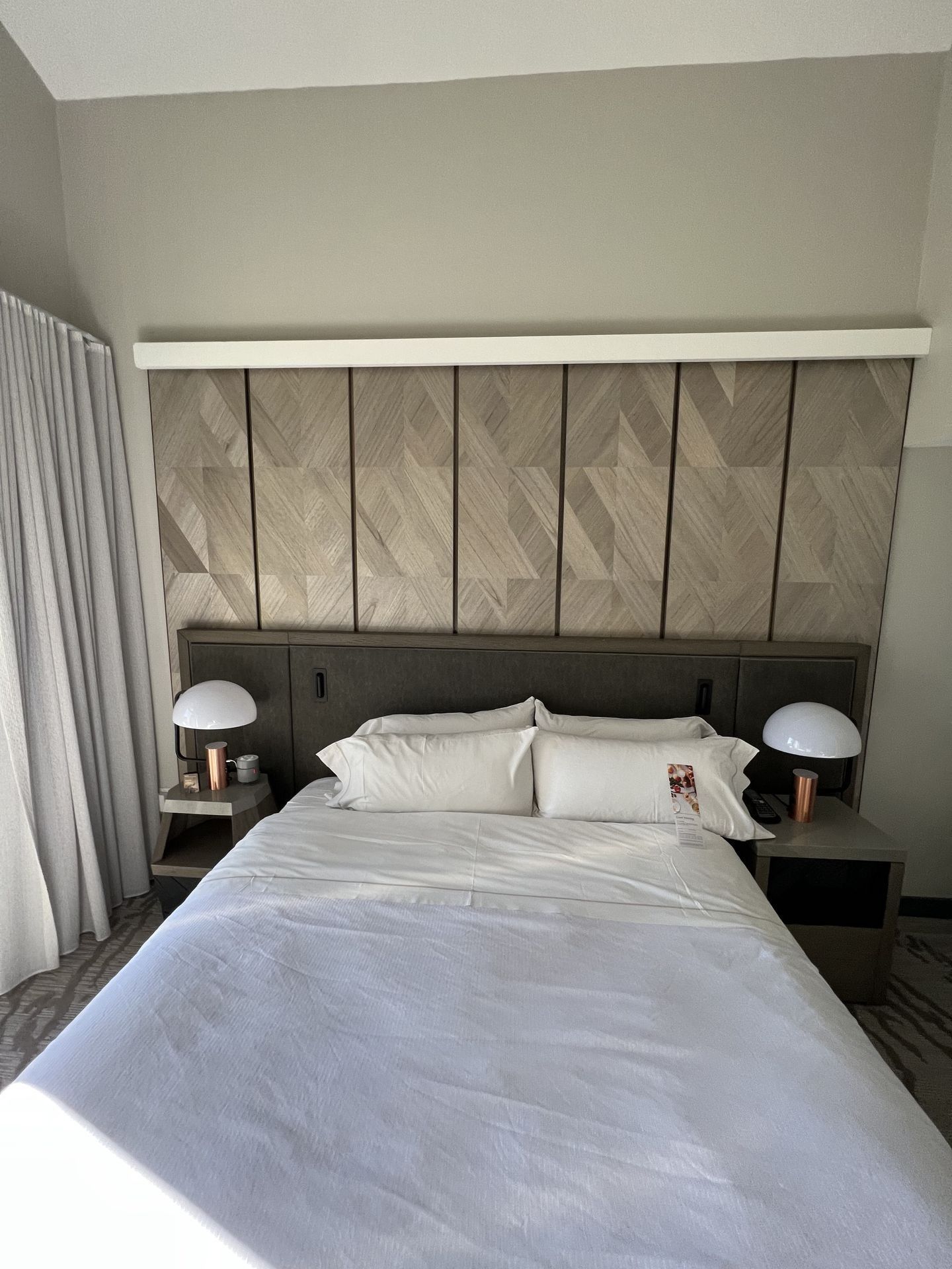 A hotel room with a bed and two lamps