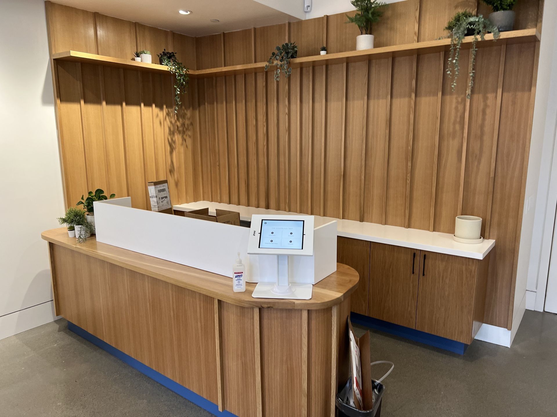 A wooden reception desk with a hand sanitizer dispenser in a room.