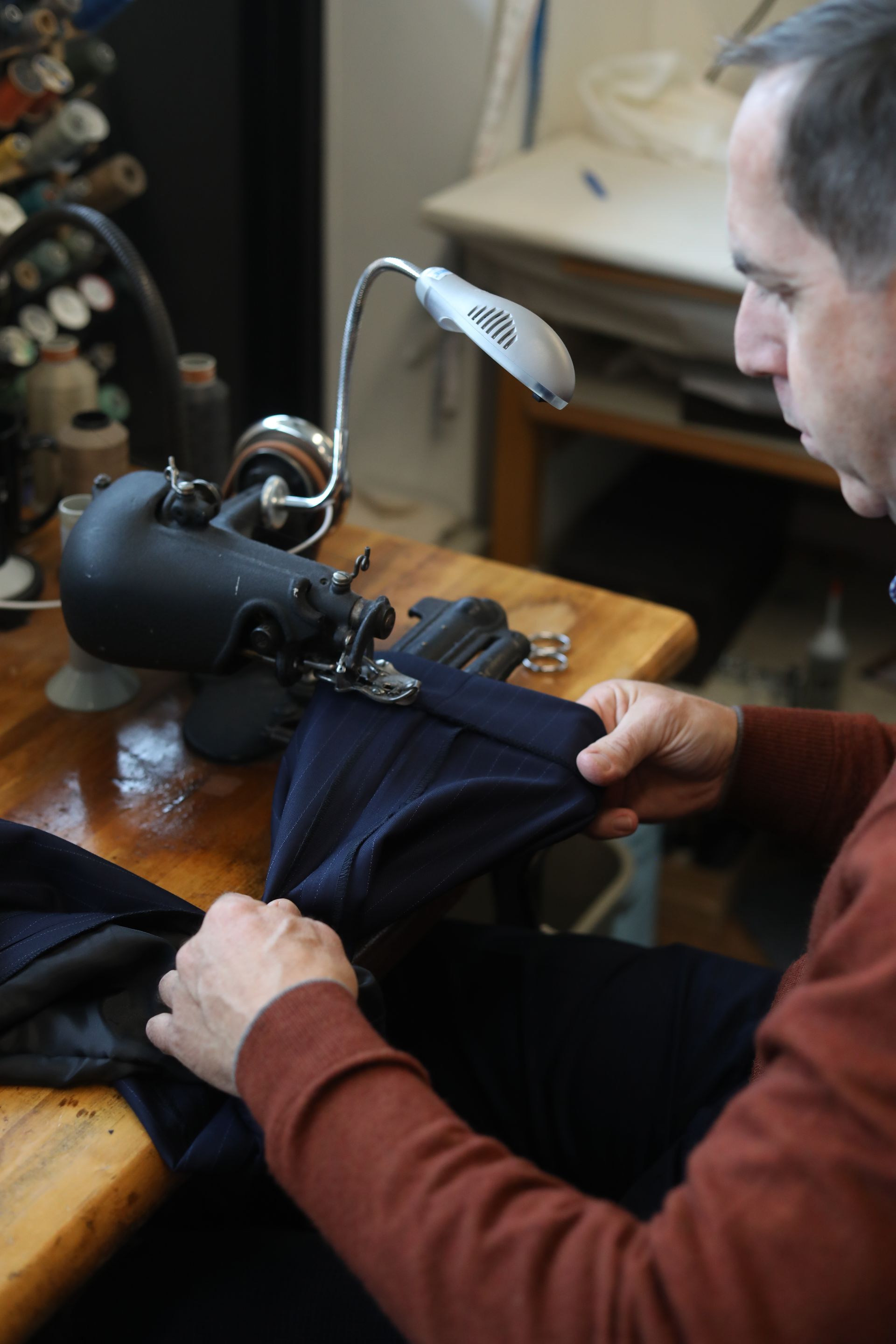 A man is sitting at a table using a sewing machine