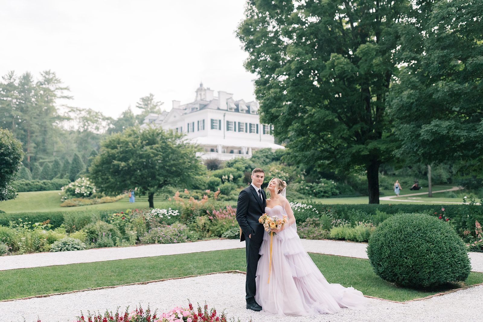 A bride and groom are posing for a picture in front of a large white building.