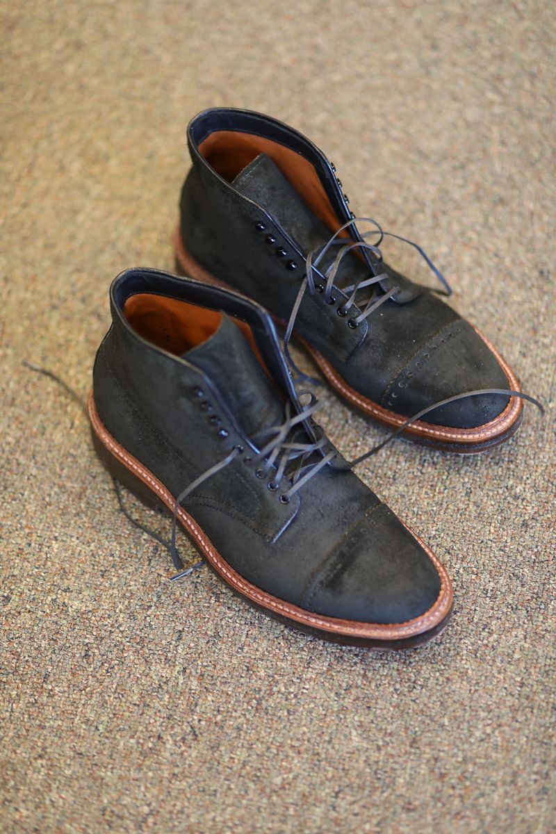 A pair of black boots are sitting on a carpet.