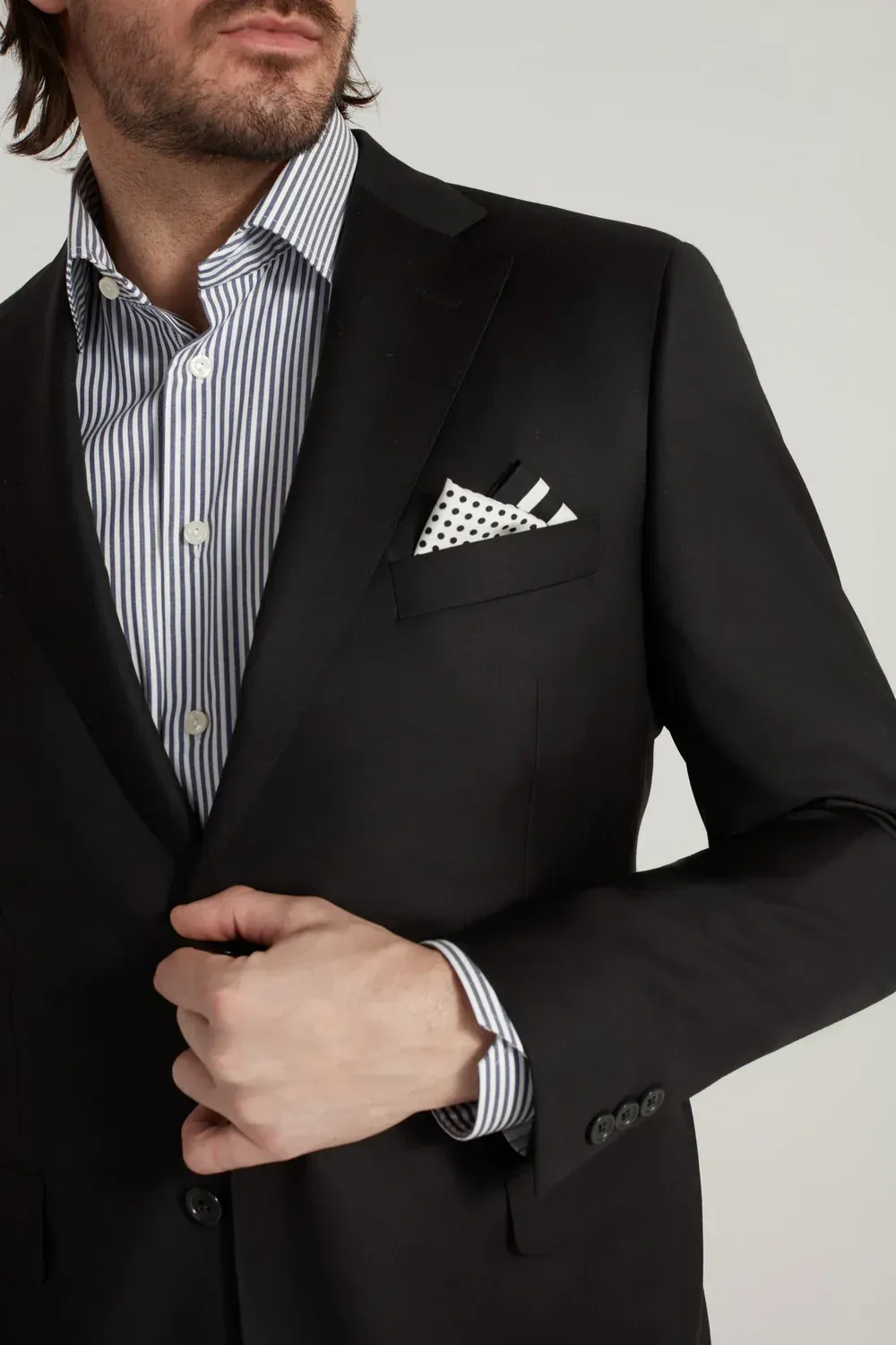 A man in a black suit has a pocket square in his pocket