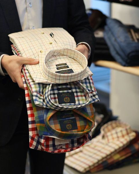 A man in a suit is holding a stack of shirts