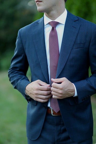 A man in a suit and tie is adjusting his jacket.