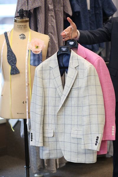 A man is looking at a suit jacket on a mannequin.