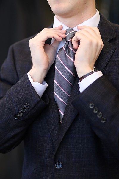 A man in a suit is tying his tie