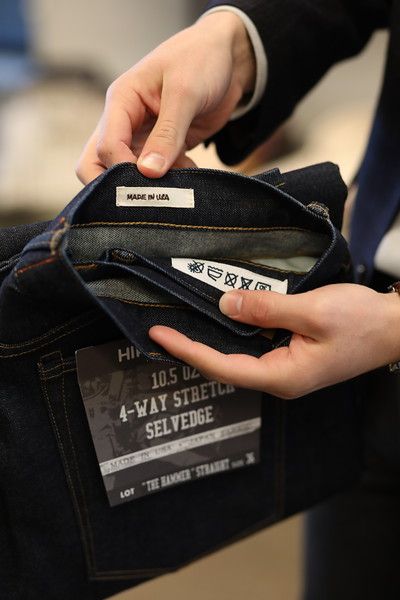 A person is holding a pair of 4 way stretch selvedge jeans