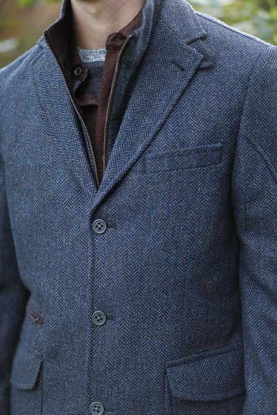 A man is wearing a blue jacket and a brown shirt.