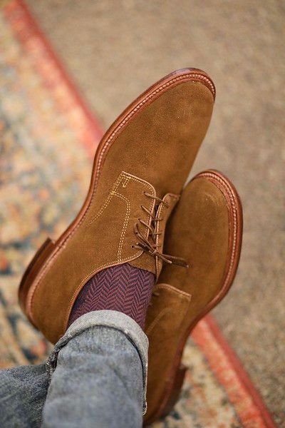 A person wearing a pair of brown shoes and purple socks.