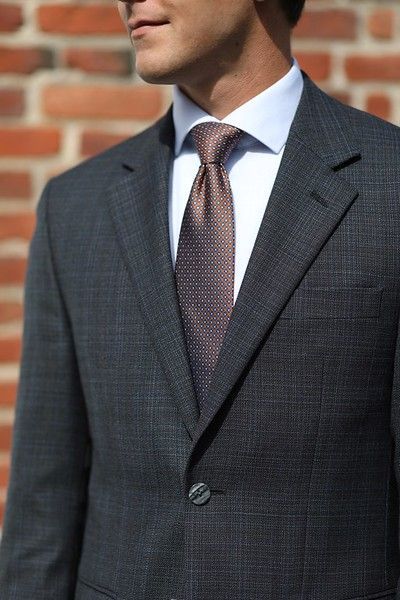 A man in a suit and tie is standing in front of a brick wall