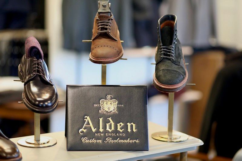Three shoes are displayed on a table with a sign that says ' alden ' on it.