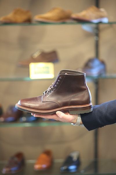 A person is holding a pair of brown boots in their hand.