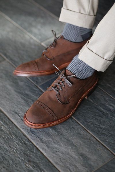 A person wearing a pair of brown shoes and grey socks