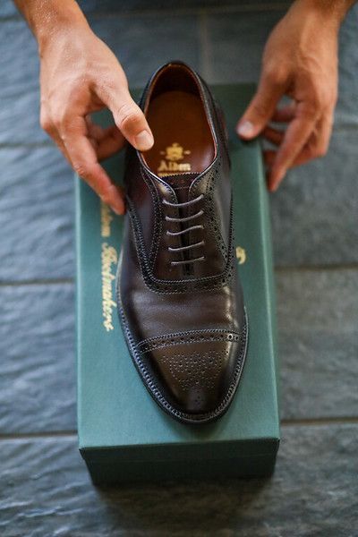 A person is putting a pair of brown shoes on a green box