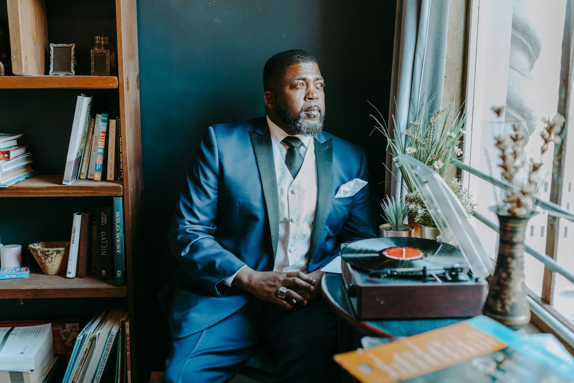A man in a suit and tie is sitting in front of a record player.