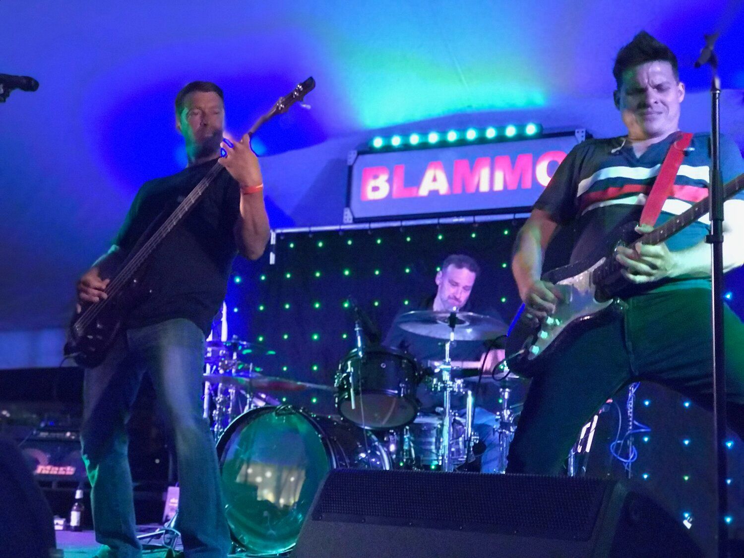 A man playing a guitar in front of a sign that says blammo