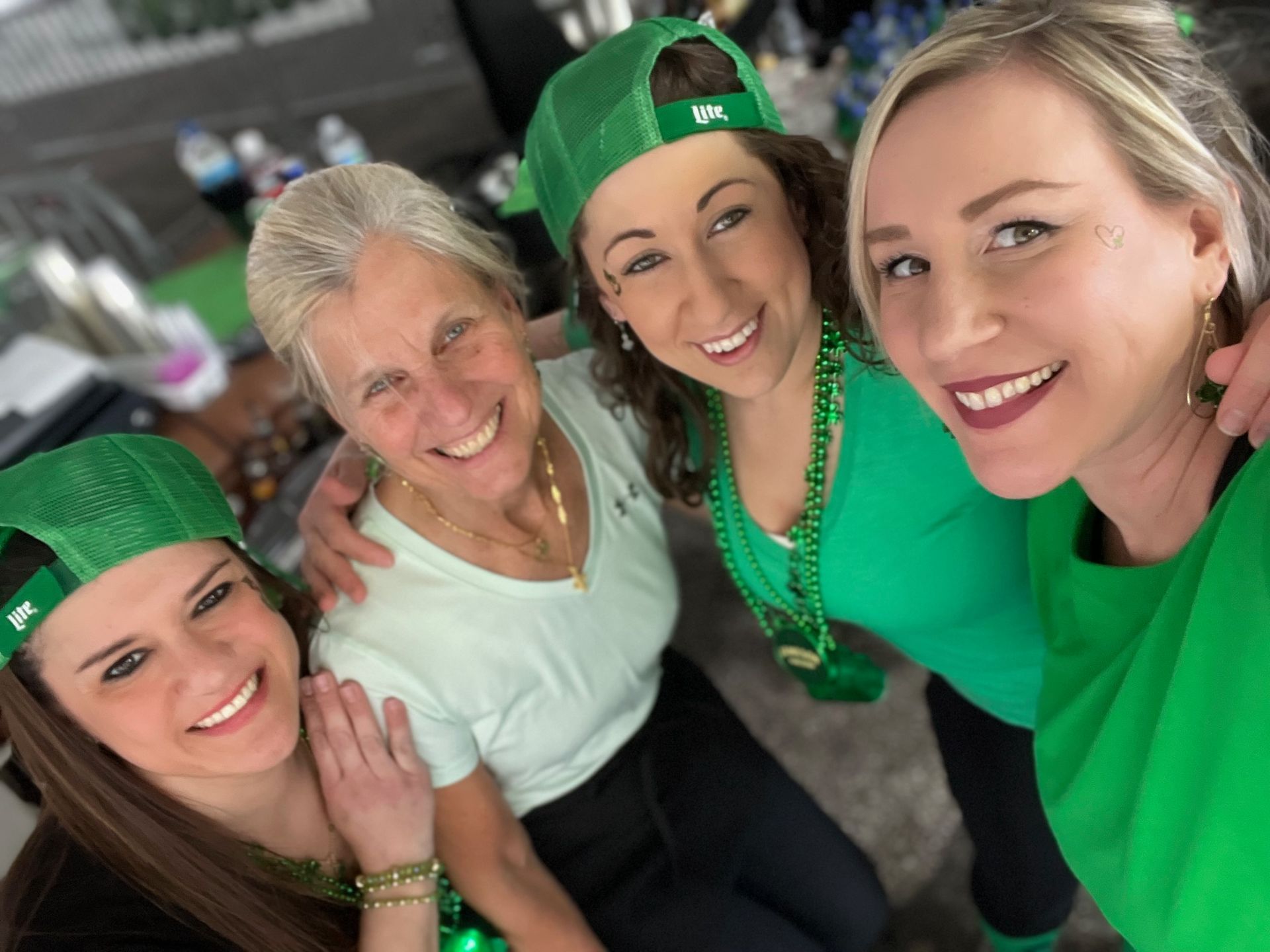 A group of women wearing green shirts and hats are posing for a picture.