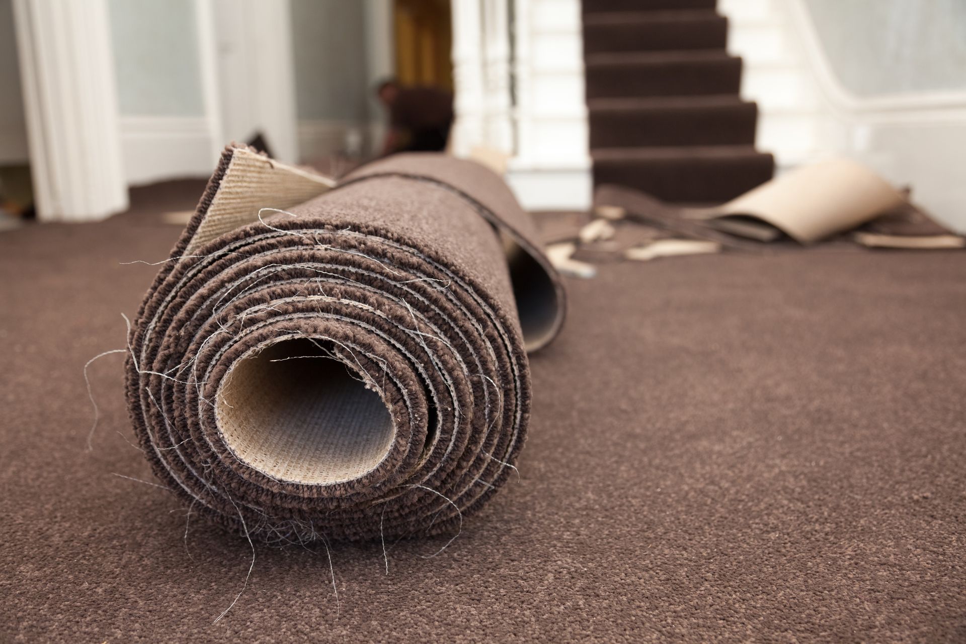 A roll of brown carpet is laying on the floor in a room.