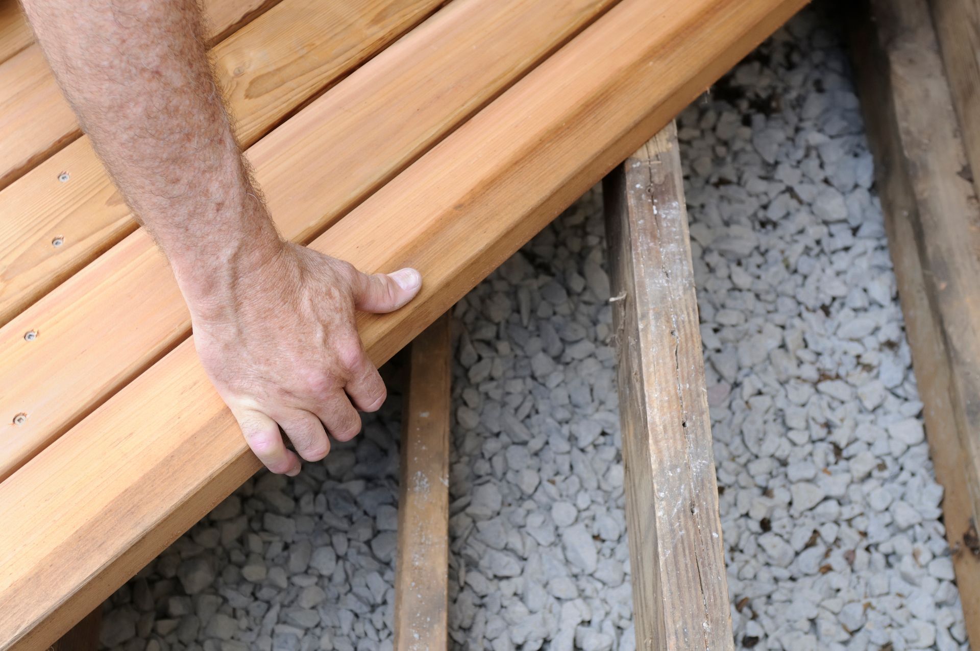 A person is holding a piece of wood on a deck.