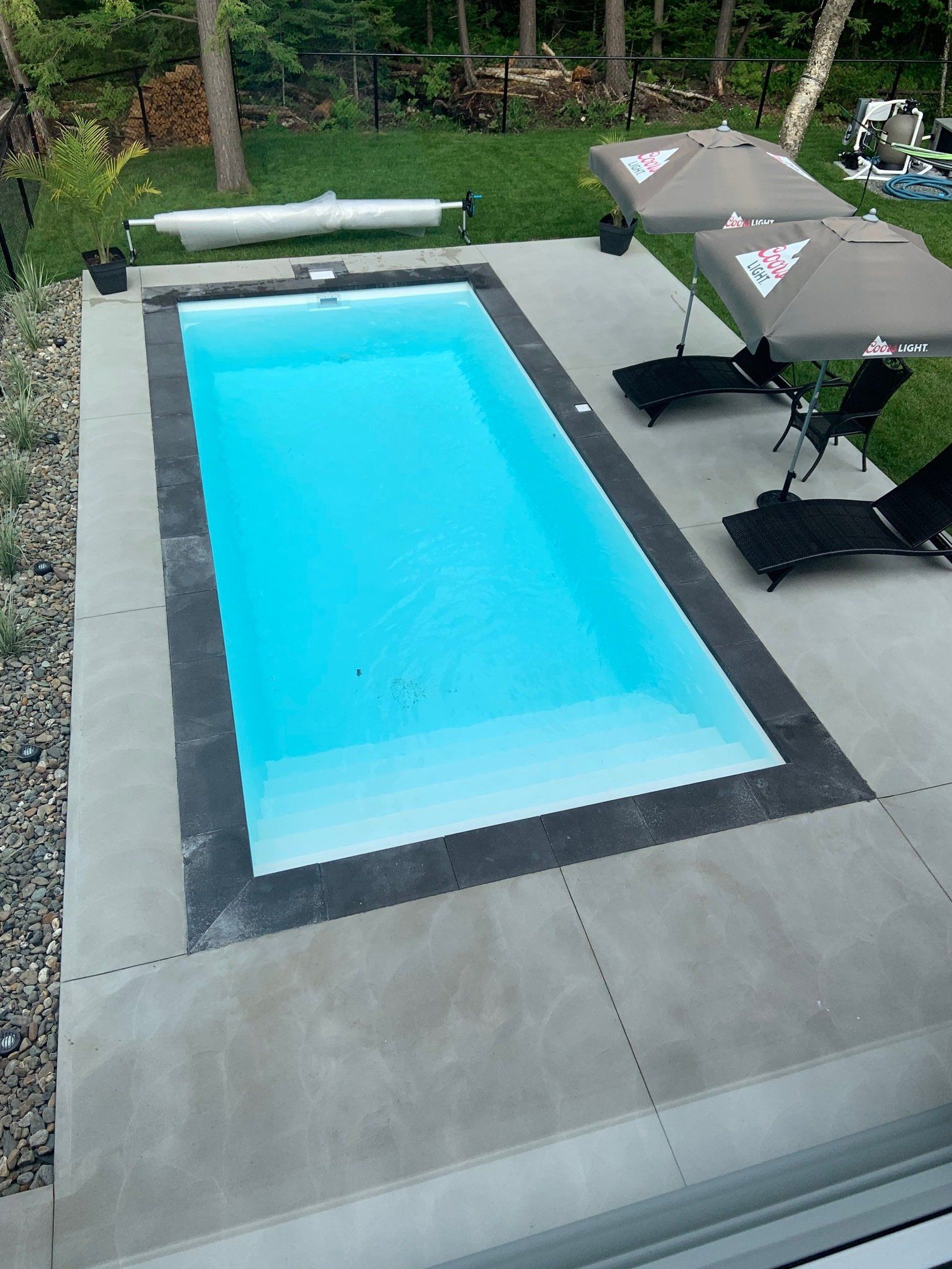 Une grande piscine entourée de chaises et de parasols dans une cour arrière.