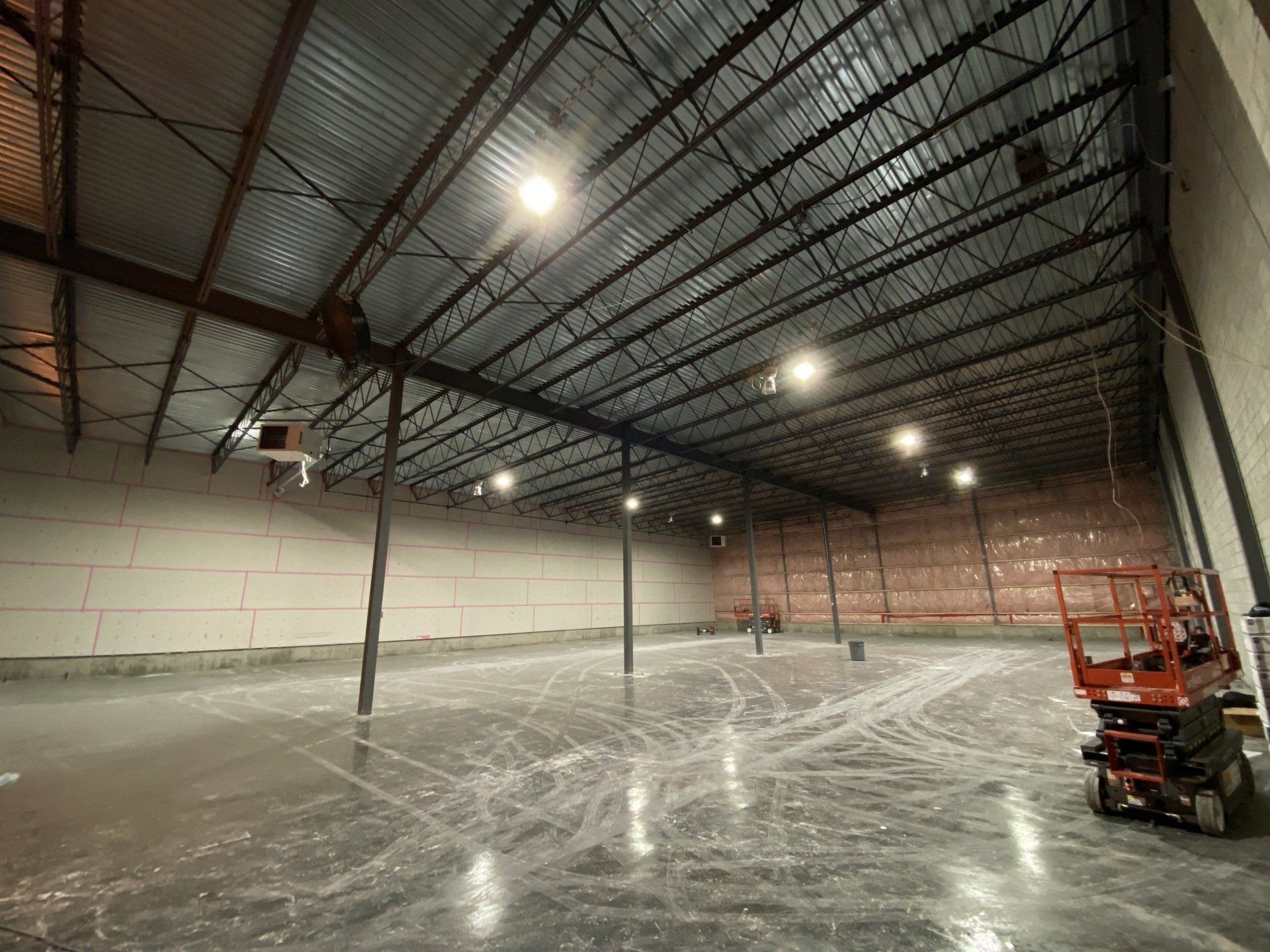 Un grand entrepôt vide avec un chariot élévateur au milieu.