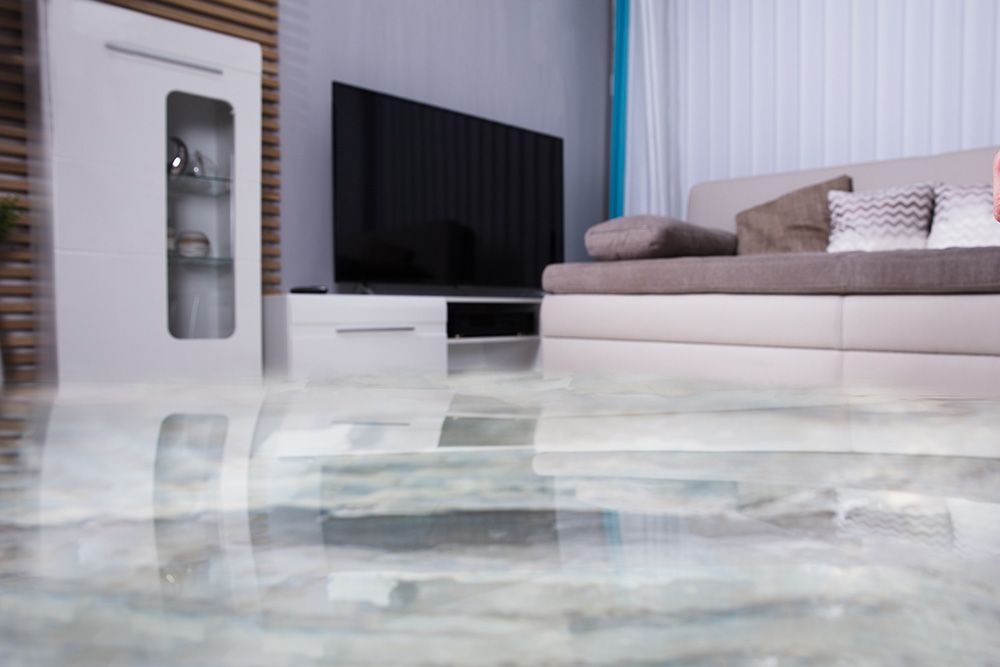 Un salon avec un sol inondé et un canapé et une télévision.