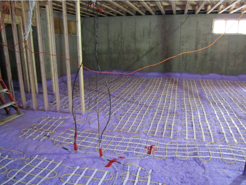 Un sous-sol en construction avec isolation violette et fils électriques