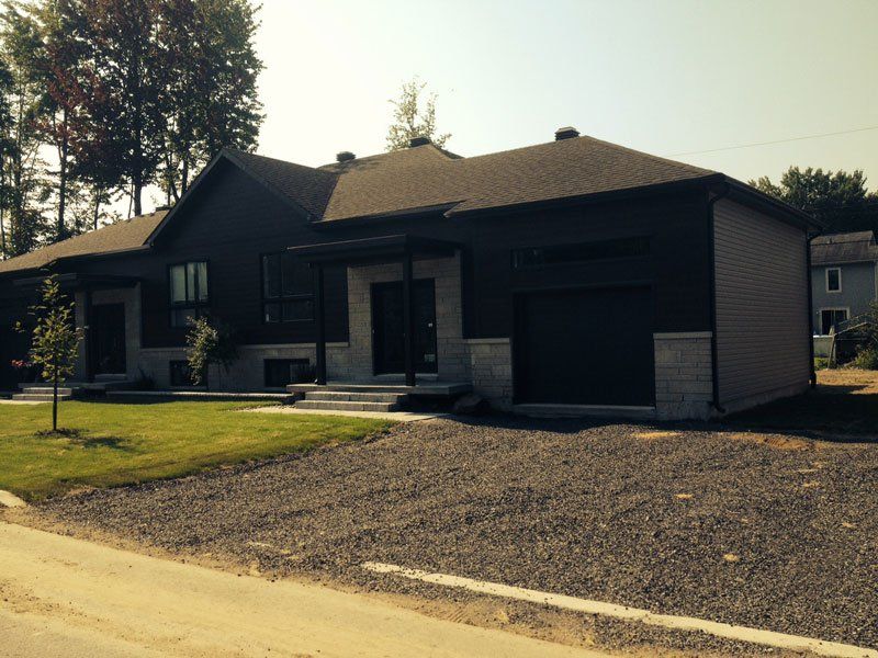 Une maison avec deux garages et une allée en gravier