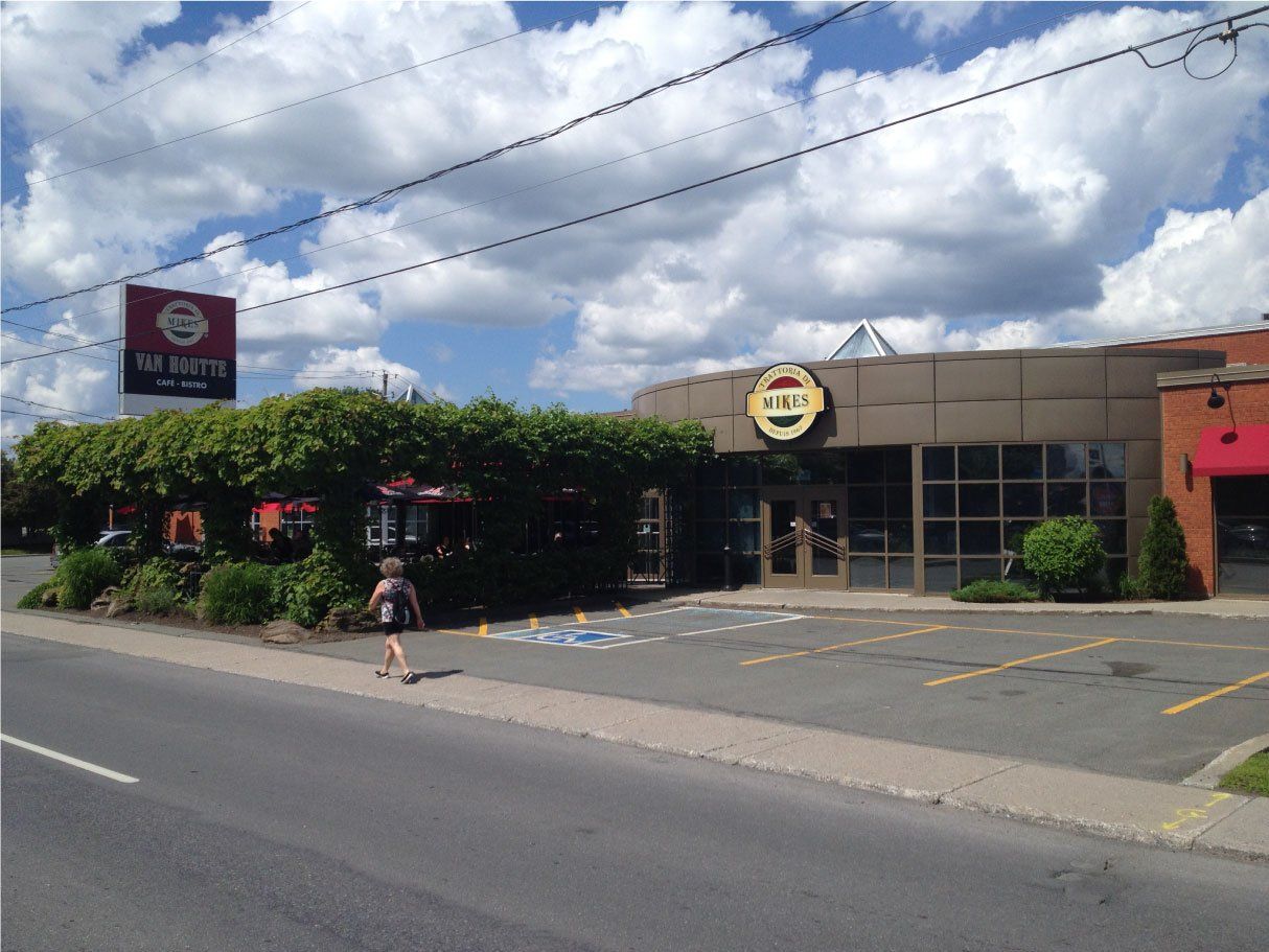 Une personne marche sur le trottoir devant un restaurant