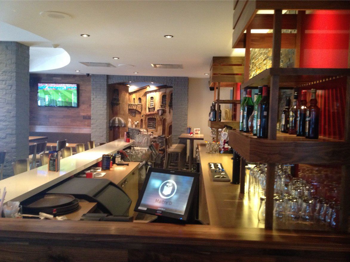 Un bar avec des bouteilles sur des étagères et une télévision sur le mur