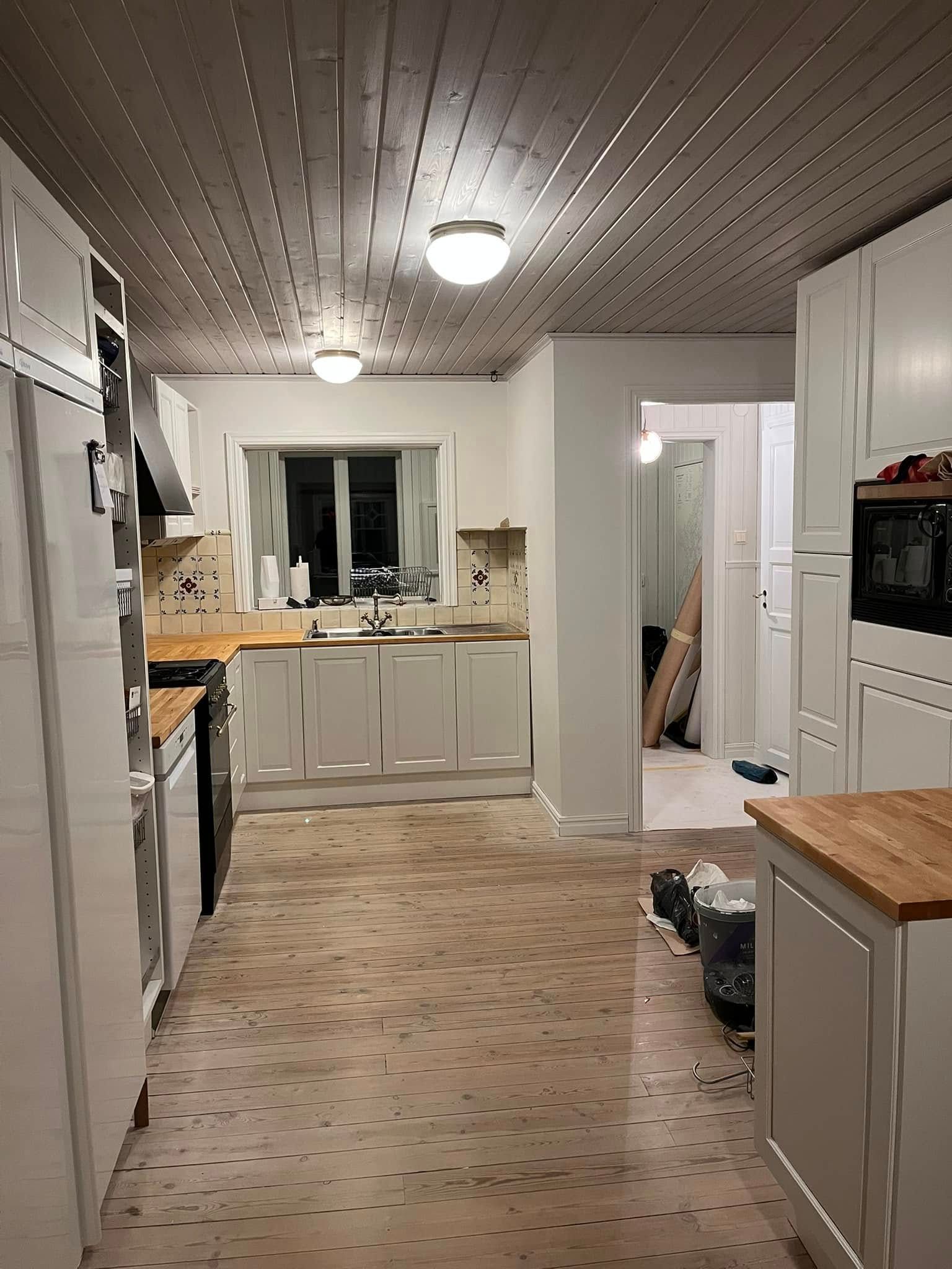 A kitchen with white cabinets and a wooden floor.