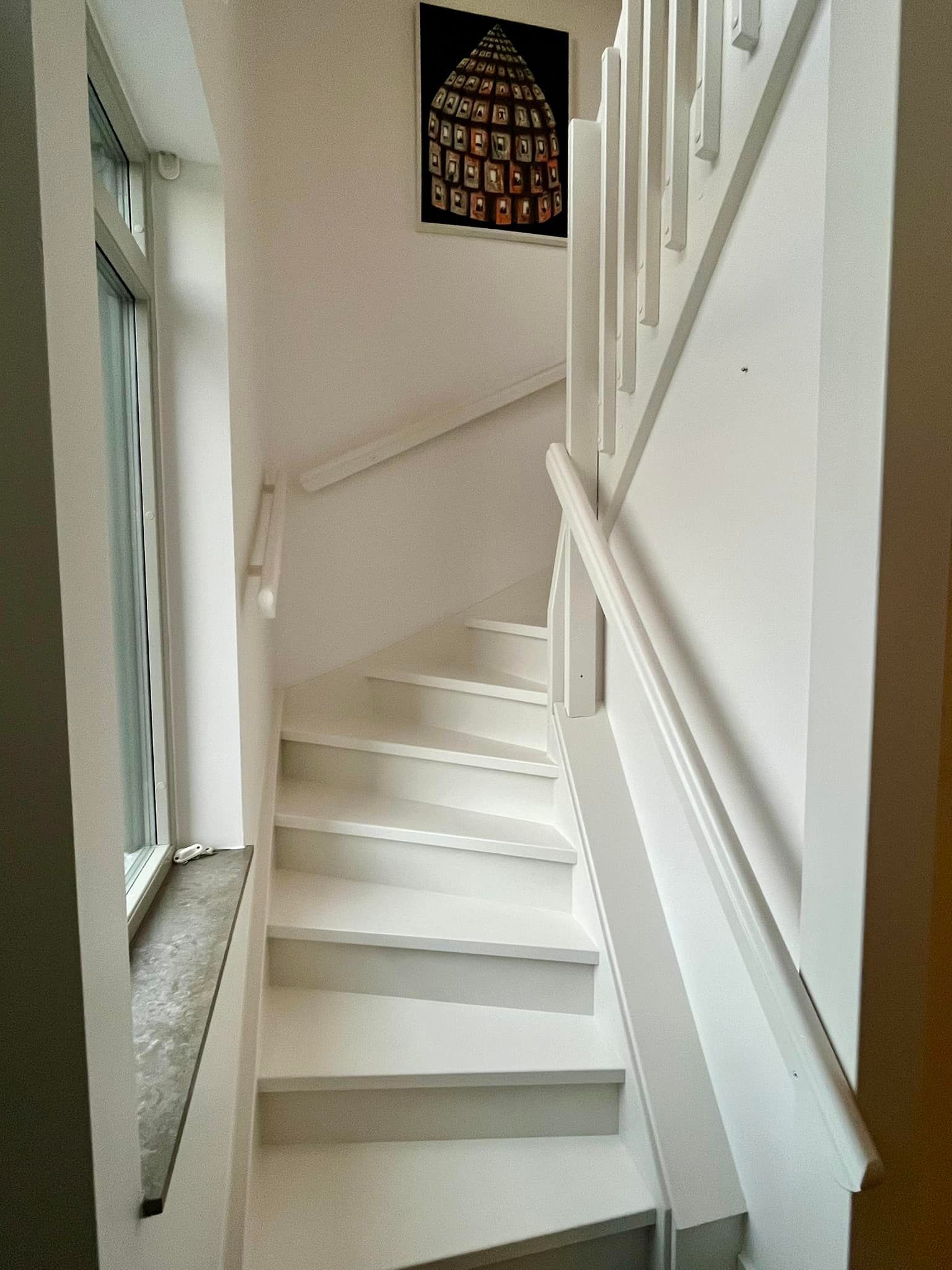 A white staircase with a picture on the wall above it