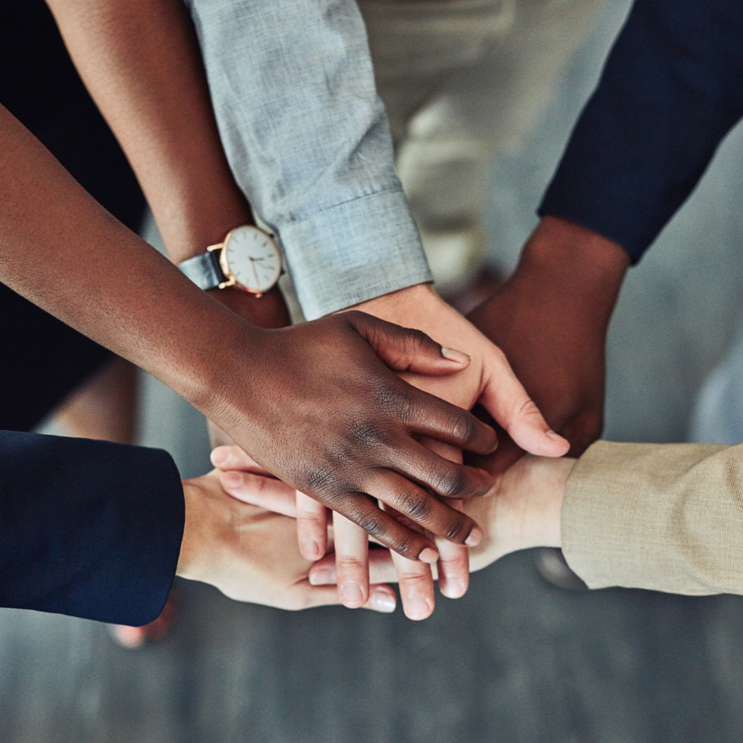 A group of people are putting their hands together