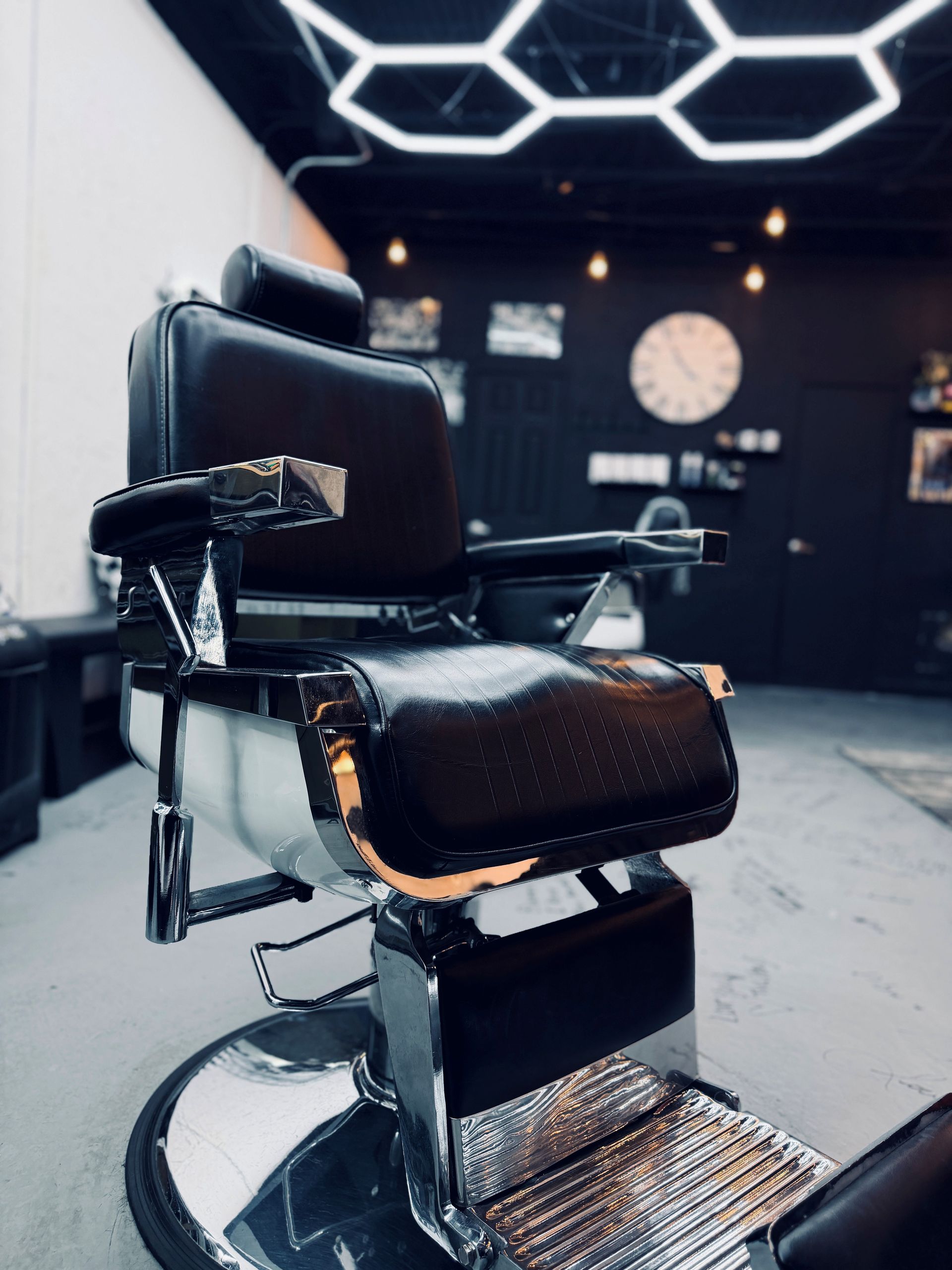 A vintage-style brown leather barber chair with white trim and chrome accents, positioned in a dimly lit setting.
