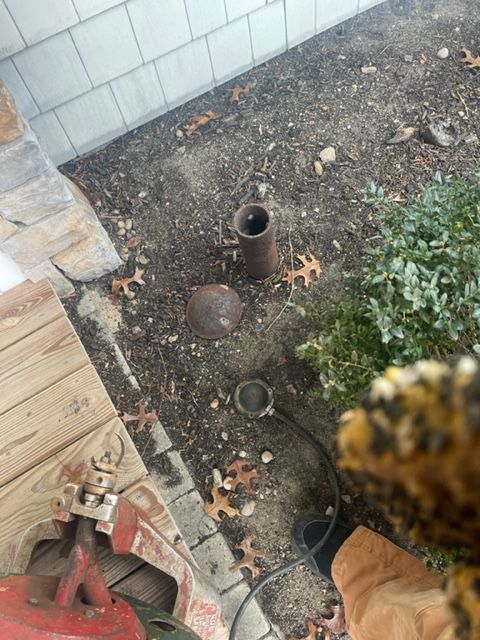 a person is working on a pipe in the dirt near a house .