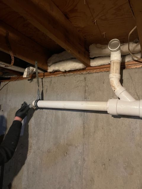 a person is working on a pipe in a basement .